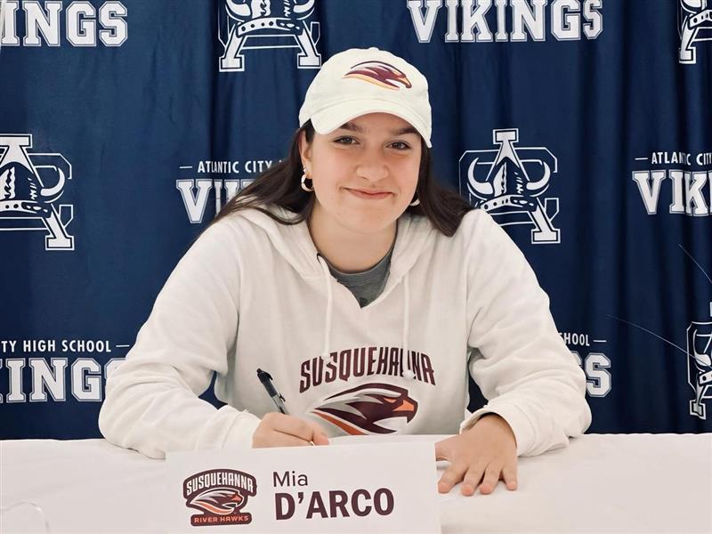 Mia D'Arco sits at a table before signing letter from Susquehanna University.